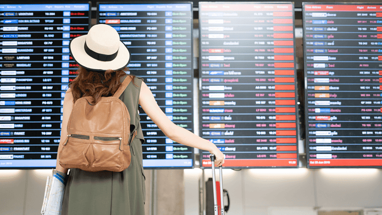Woman standing in front of flight board in airport